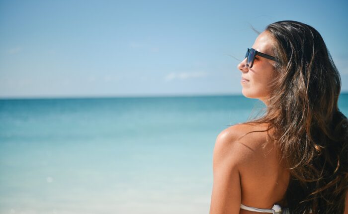 a woman in a garment and sunglasses on a beach