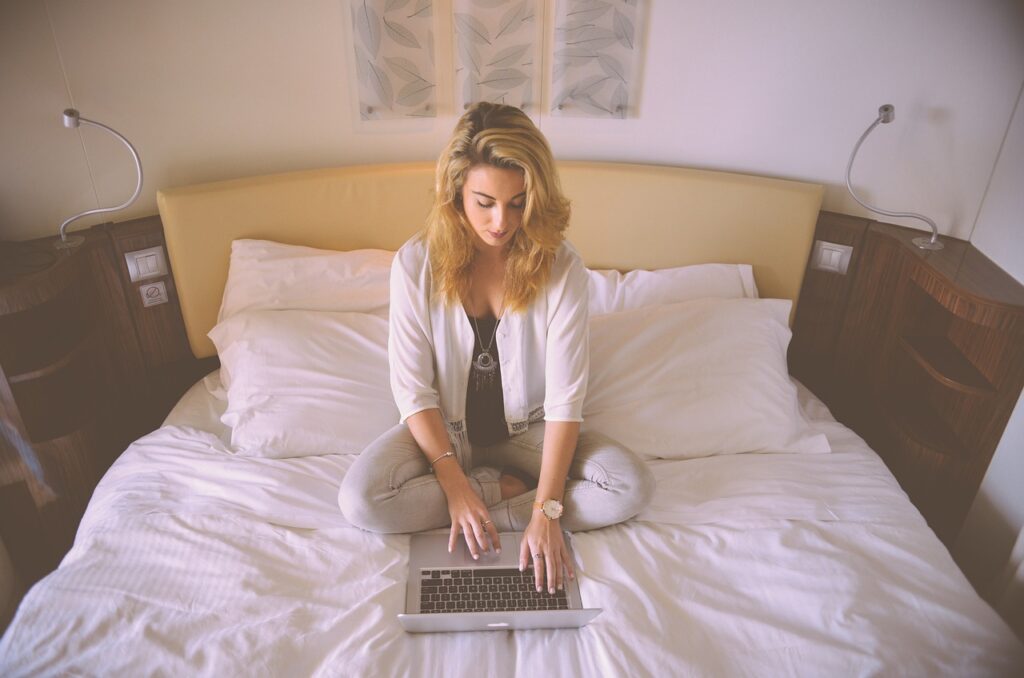 a woman sitting on a bed using a laptop