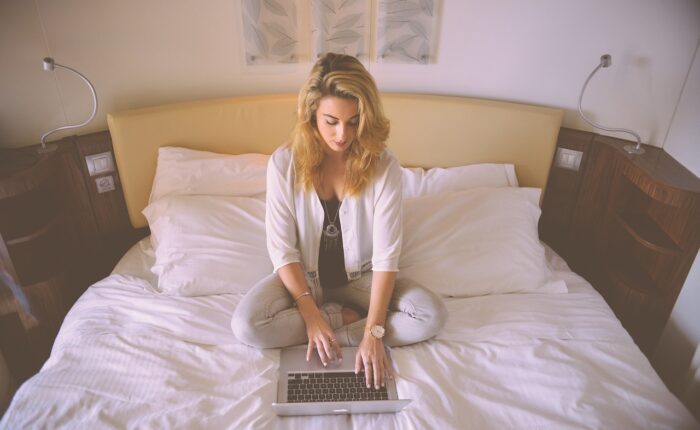 a woman sitting on a bed using a laptop