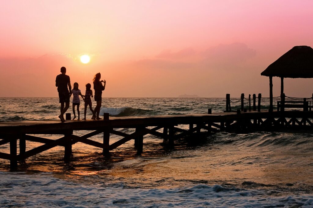 a group of people walking on a dock at sunset